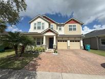 Charming two-story home with a well-manicured lawn, lush landscaping, and a brick driveway at 8986 Fullerwood Ave, Orlando, FL 32832