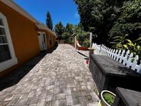 Charming backyard with a brick paver patio, a white picket fence, a relaxing hammock, and lots of greenery at 10207 Cody Ln, Orlando, FL 32825
