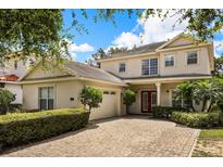 Charming two-story home featuring a red front door, brick driveway, and well-manicured landscaping at 1225 Radiant St, Reunion, FL 34747