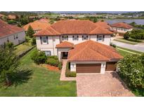 Elegant two-story home featuring a red tile roof, manicured lawn, and a spacious three-car garage at 1776 Bella Lago Dr, Clermont, FL 34711