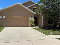 Two-story home with a two-car garage, tan exterior, and a well-manicured front yard with a large tree at 2106 Congress Ln, St Cloud, FL 34769