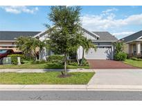 Charming single-story home with manicured landscaping, a brick driveway, and a two-car garage at 2772 Southland St, St Cloud, FL 34772