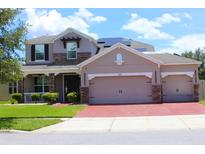 Charming two-story home with a three car garage, stone accents, and a well-manicured lawn at 2805 Carter Grove Ln, Kissimmee, FL 34741