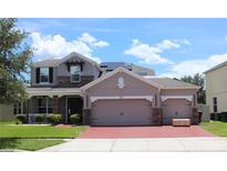 Charming two-story home with a brick driveway and stone accents, plus a three-car garage for ample parking at 2805 Carter Grove Ln, Kissimmee, FL 34741