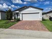 Charming single-story home with a brick driveway and attached two-car garage at 3839 Marbella Way, Davenport, FL 33897