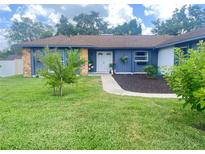 Charming blue home with stone accents, lush lawn, and walkway to the front door at 421 Bridle Path, Casselberry, FL 32707