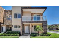 Stylish two-story townhouse featuring a balcony, stone accents, and lush landscaping at 7628 Recife Dr, Kissimmee, FL 34747