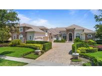 Beautifully landscaped front exterior featuring a paved drive, lush greenery and a meticulously kept lawn at 9905 Lanai View Ct, Windermere, FL 34786