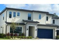 Modern two-story home with a stone entryway, dark blue garage door, and well-maintained landscaping at 1283 Butterfly, Davenport, FL 33837