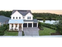 Stunning two-story home with three-car garage and inviting front porch overlooking a tranquil lake at 14081 Gullstrand Ave, Orlando, FL 32827