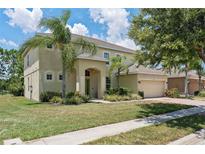 Two-story home with well-manicured lawn, colorful flowerbeds, arched entry, and attached two-car garage at 256 Yellow Snapdragon Dr, Davenport, FL 33837