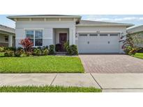 Charming home featuring a manicured lawn, brick paver driveway, and two-car garage at 2621 Redblush Ter, St Cloud, FL 34772