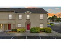 Tan two-story townhouse featuring a red front door, tidy landscaping, and convenient parking at 2867 Club Cortile Cir, Kissimmee, FL 34746