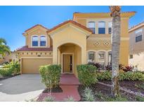 Charming two-story home with terra cotta roof, arched entry, and mature landscaping at 477 Orange Cosmos Blvd, Davenport, FL 33837