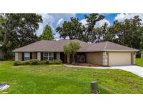 Charming single-story home with a well-manicured lawn and a two car garage at 1405 Ashbury Ct, Lakeland, FL 33809