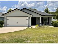 Charming single-story home with a well-manicured lawn and a two-car garage, showcasing inviting curb appeal at 144 Foxtail Loop, Davenport, FL 33837