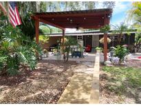 Inviting patio with pergola and outdoor grill, surrounded by lush landscaping and an American flag at 2082 Starboard Dr, Geneva, FL 32732