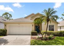 Charming single-story home featuring a two-car garage, manicured lawn, and tropical landscaping at 2263 Mallory Cir, Haines City, FL 33844