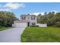 Two-story home featuring gray siding, black shutters, a well-manicured lawn, and an attached garage at 303 Anchovie Ct, Poinciana, FL 34759