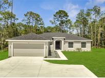 Charming single-story home featuring a well-manicured lawn, two car garage, and welcoming entrance at 33 Peterlee Ct, Kissimmee, FL 34758