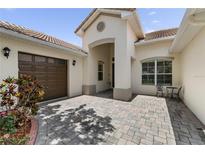 Charming, light-colored home featuring a well-manicured front yard, brown garage door and a cozy table and chairs on the side at 3856 Shoreside Dr, Kissimmee, FL 34746