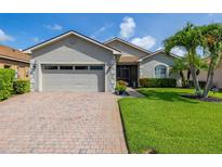 Charming single-story home with a brick driveway, two-car garage, and a beautifully manicured lawn at 4056 Ashton Club Dr, Lake Wales, FL 33859