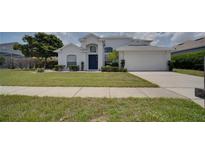 Beautiful home featuring a well-manicured lawn, lush shrubbery, and a classic two-car garage at 408 Bloomingdale Dr, Davenport, FL 33897