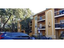 Condominium exterior with a yellow facade, multiple balconies, and a view of the surrounding greenery at 5287 Images Cir # 307, Kissimmee, FL 34746