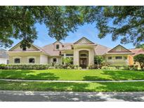 Elegant single-story home featuring lush landscaping, manicured lawn, and a beautiful light beige stucco exterior at 8214 Lake Serene Dr, Orlando, FL 32836