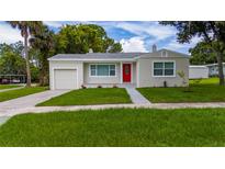 Charming single-story home featuring a red front door, well-maintained lawn, and attached garage at 113 W Division St, Winter Garden, FL 34787