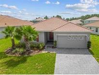 Charming single-story home featuring a tile roof, manicured lawn, paver driveway, and a two-car garage at 1416 Oak Marsh St, Davenport, FL 33837