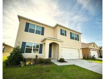 Two story home with blue shutters, well-manicured lawn, and attached two car garage at 1591 Barberry Dr, Kissimmee, FL 34744