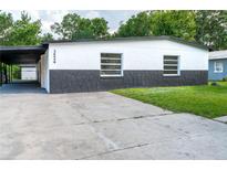 Charming one-story home with carport, showcasing black and white color scheme, and a well-maintained yard at 3524 Hage Way, Orlando, FL 32805