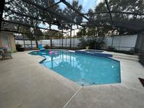 Screened-in pool and spa with concrete deck and clear blue water, with privacy fence and trees at 4820 Wingrove Blvd, Orlando, FL 32819
