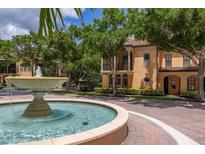 Beautiful two-story, tan-colored home featuring a fountain and mature landscaping enhancing the curb appeal at 502 Mirasol Cir # 103, Kissimmee, FL 34747