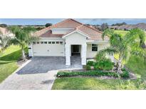 Charming home boasts a tile roof, brick paver driveway, two-car garage, and lush tropical landscaping at 8990 Ace Loop, Champions Gate, FL 33896