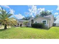 Inviting one-story home featuring a well-maintained lawn and lush palm trees at 283 Pine Arbor Dr, Orlando, FL 32825