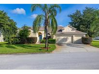 Charming single-story home with a well-manicured lawn, mature landscaping, and an attached two-car garage at 305 Grand Reserve Dr, Davenport, FL 33837