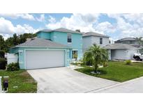 Charming two-story home featuring a two-car garage, palm tree, and well-manicured lawn on a sunny day at 336 Hollingshead Loop, Davenport, FL 33896
