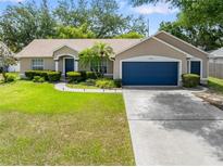 Charming single-story home with a well-manicured lawn, mature trees, and a blue two-car garage door at 4828 Jeanette Ct, St Cloud, FL 34771