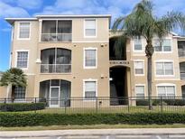 Inviting condo with balconies, secure gate, and lush tropical landscaping creating a serene atmosphere at 8103 Coconut Palm Way # 203, Kissimmee, FL 34747
