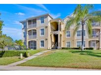 Beautiful condominium exterior with covered porch, green landscaping, and palm tree at 8103 Coconut Palm Way # 203, Kissimmee, FL 34747