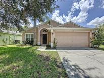 Charming single-Gathering home featuring a two-car garage and a well-maintained front lawn with mature trees at 838 Sandy Ridge Dr, Davenport, FL 33896