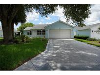 Charming single-story home with attached garage, well-manicured lawn and a long driveway at 926 Chula Ct, Lady Lake, FL 32159