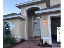 Inviting home featuring a welcoming front entrance with an arched entryway, brick path, and manicured landscaping at 117 Winchester Ln, Haines City, FL 33844