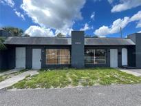 Low-rise commercial building with a symmetrical design, painted dark gray, under a partly cloudy sky at 4950 Silver Star Rd, Orlando, FL 32808