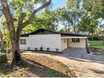 Charming home with a white exterior, black roof, and a covered carport at 7043 Carlene Dr, Orlando, FL 32835