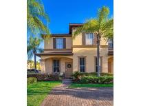 Charming two-story townhome featuring a welcoming porch, lush landscaping, and two palm trees enhancing curb appeal at 746 Terra Lago St, Davenport, FL 33897