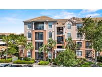 Beautiful condominium building featuring a tile roof, multiple balconies, and tropical landscaping at 1351 Venezia Ct # 201, Davenport, FL 33896