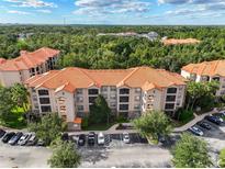 Scenic aerial view of complex with terracotta roofs, lush landscaping, and ample parking at 1361 Tuscan Ter # 7303, Davenport, FL 33896
